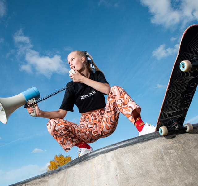 Девушка в футболке Такие дела с мегафоном и скейтом на бетонном блоке